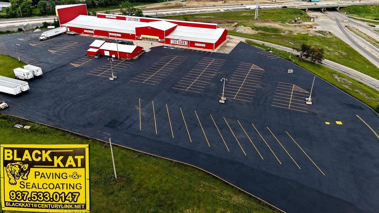 Aerial view of a large commercial parking lot freshly sealcoated and striped by Blackkat Paving